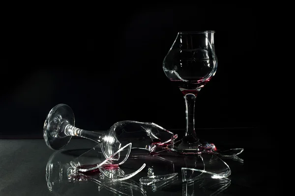 Red Wine in Broken Glass Cups Spilled on the Glass Table Isolated on Black — Stock Photo, Image