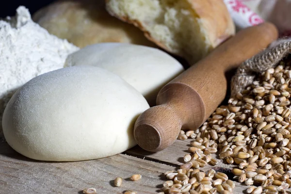 Nudelholz mit Teig und Weizen auf Holztisch — Stockfoto