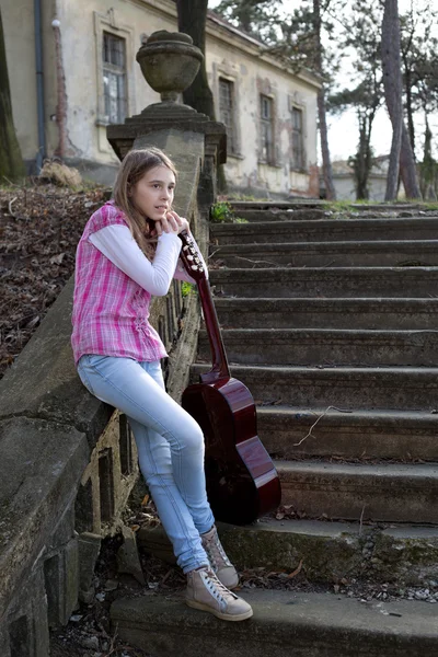 Adolescente pensive fille avec jambes croisées s'appuyant sur la guitare de plein air — Photo