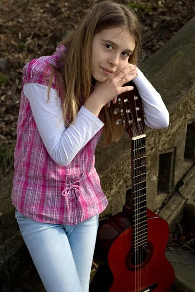 Jeune fille s'appuyant sur la guitare et regardant la caméra extérieure — Photo