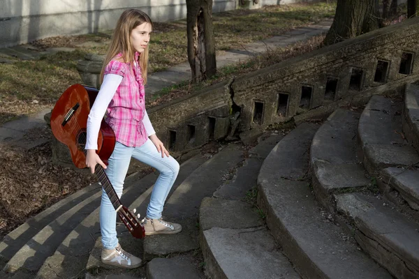 Jeune fille avec guitare dans la main montant les escaliers dans le parc le jour ensoleillé — Photo