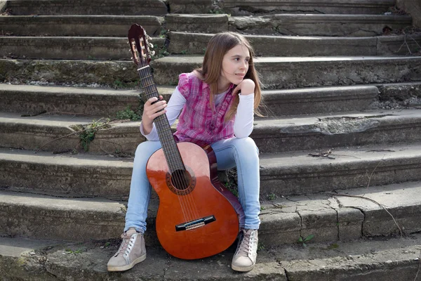 Belle jeune fille avec guitare assis sur les escaliers en plein air et regardant loin — Photo