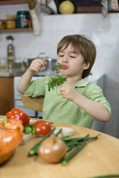 Little Boy Making Funny Face While Eating Parsley in the Kitchen — Stock Photo, Image
