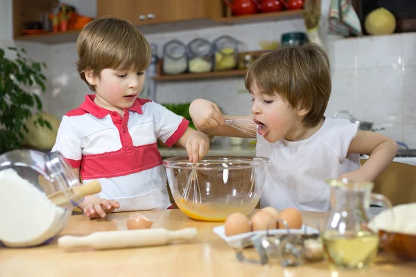 Cute Boy Licking Whisk While His Twin Brother Mixing Eggs in Mixing Bowl in the Kitchen