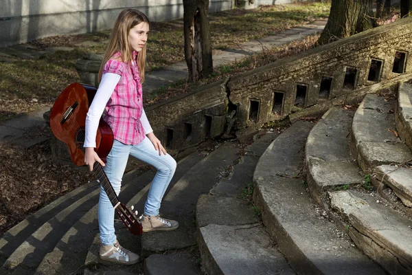 Jeune fille avec guitare dans la main montant les escaliers dans le parc le jour ensoleillé — Photo