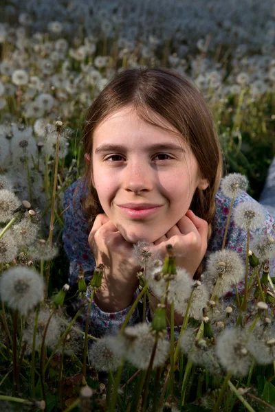 Nahaufnahme Porträt eines hübschen Mädchens, das an einem sonnigen Frühlingstag auf einem Löwenzahnfeld ruht — Stockfoto