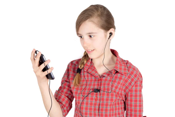 Vista lateral da menina sorridente com fones de ouvido ouvindo música em seu celular isolado no branco — Fotografia de Stock