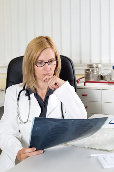 Médecin féminine inquiète examinant les rayons X d'un patient souffrant d'un cancer du poumon dans une salle de consultation — Photo