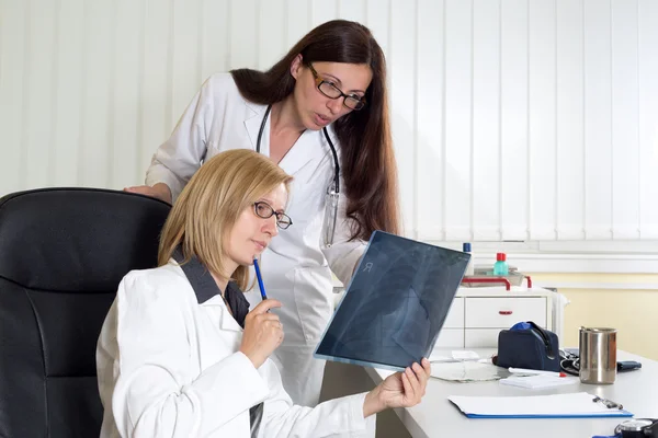 Женщины-врачи, анализирующие рентгеновские снимки пациентов, страдающих от рака легких в больнице Лицензионные Стоковые Фото