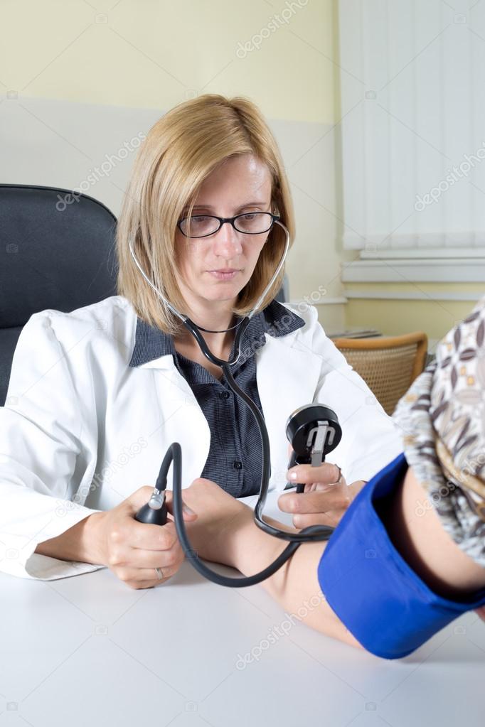 Doctor Measuring Blood Pressure With Stethoscope and Sphygmomanometer in Consulting Room