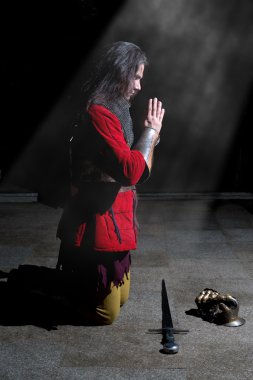Şövalye dizlerinin üzerine diz çökmüş ve ışık ışınları dua