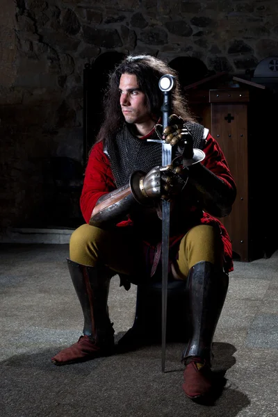 Guerrero medieval con espada sentado en la vieja iglesia — Foto de Stock