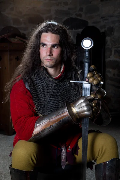 Knight With Sword Sitting Against Old Stonewall and Looking Away — Stock Photo, Image