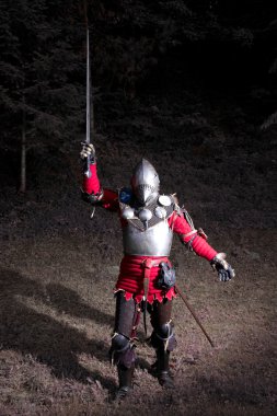 Knight gece ormanda yükseltilmiş elinde kılıç ile