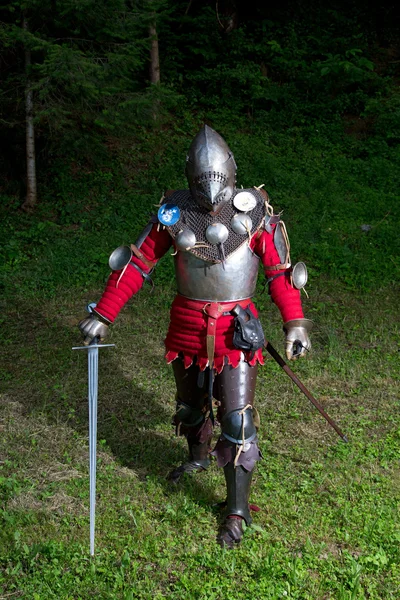 Porträt eines Ritters in Rüstung mit Helm und Schwert im Wald — Stockfoto