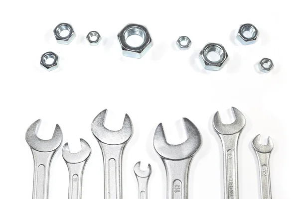 Heap Of Wrenches Of Different Sizes Against Nuts Of Different Sizes Isolated On White Background — Stock Photo, Image