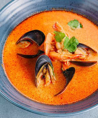 Tom Yum Thai sıcak baharatlı karides ve somut arka planda midye Tayland yemeği