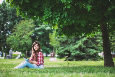 Genç güzel kadın parkta telefonda söz. 