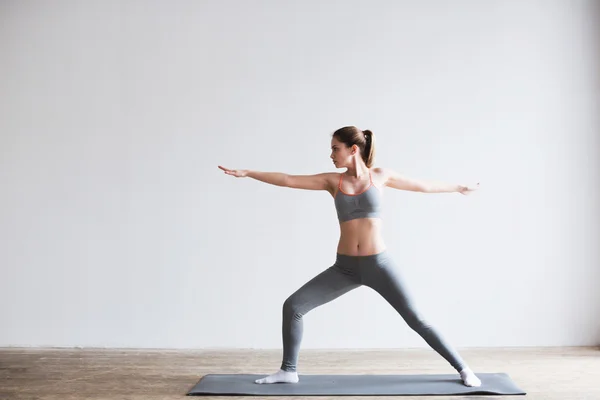 Jonge mooie yoga poseren op mat binnenshuis. — Stockfoto