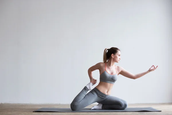 Jonge vrouw doen yoga oefening op mat. — Stockfoto