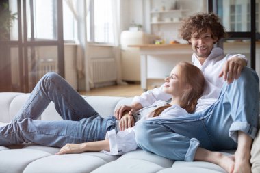 Ev hayatının tadını çıkarıyorum. Mutlu genç çift evdeki kanepede dinleniyor..