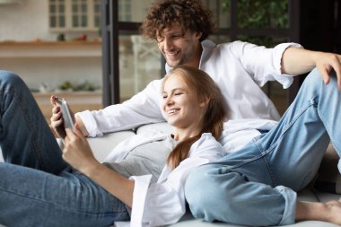 Evdeki kanepede sevgili bir çift ve dijital tablet kullanıyorlar. İnternetten alışveriş.