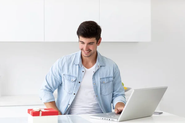 Sorrindo Bonito Jovem Sentado Sozinho Mesa Com Laptop Está Escolhendo — Fotografia de Stock