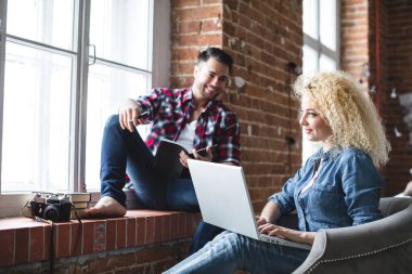 Modern çatı katında dizüstü bilgisayar kullanan mutlu bir çift. İnternetten alışveriş.