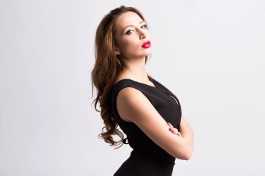 Gri arka planda poz veren siyah elbiseli güzel bir kadın..