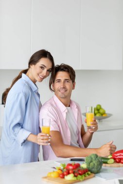 Genç mutlu çift evde sağlıklı bir yemek hazırlıyor ve eğleniyor..