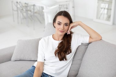 Evdeki otantik kadın portresi. Doğal bir gülümsemesi olan güzel bir kız oturma odasındaki kanepede dinleniyor.. 