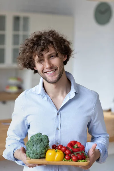 Glücklicher Junger Mann Der Gemüse Die Kamera Hält Während Hause — Stockfoto