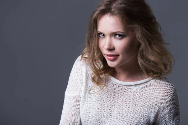 Gri arka planda gülümseyen kadının yakın plan portresi. Stüdyo çekimi. 