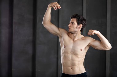 Karanlık arka planda poz veren güzel, genç ve güçlü bir adam. Stüdyo çekimi.