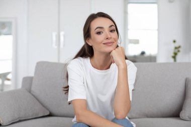 Gülümseyen mutlu kadın evdeki koltukta otururken çevrimiçi iletişim kameraya, webcam 'den görüntüye bakar..