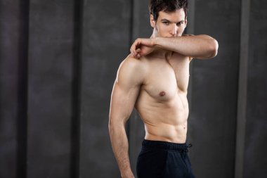 Esmer arka planda poz veren atletik bir adam. Stüdyo çekimi.