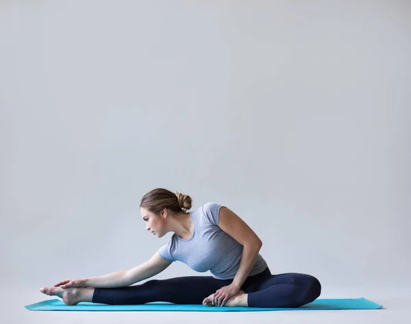 Schöne Frau Sportbekleidung Auf Einer Yogamatte Macht Dehnübungen Auf Grauem — Stockfoto