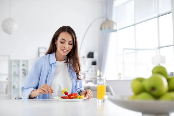 健康的な笑顔の女性食べる健全な朝食新鮮な野菜サラダでキッチンテーブルに自宅 — ストック写真