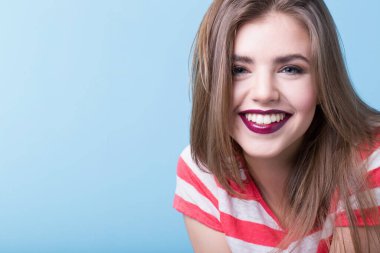 Otantik kadın portresi. Burgundy ruju ve mavi arka planda çizgili tişörtü olan gülümseyen tatlı kız..