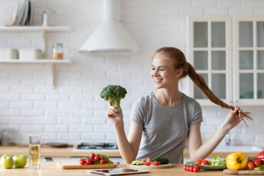 Sebze ve diyet. Ev hayatı portresi. Ev mutfağında brokoli ile gülümseyen neşeli kadın. Sağlıklı kalın.