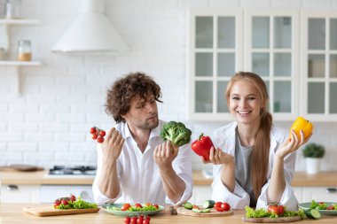 Genç ve güzel bir çift mutfakta salata pişiriyor. Sağlıklı ve sağlıklı yemekler..