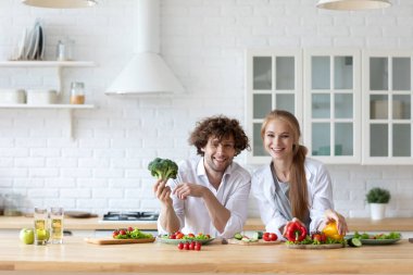 Mutfakta dikilen mutlu çift taze sebze salatası hazırlıyor. Sağlıklı yemek..