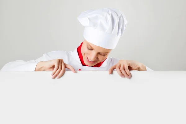 Chef mujer sosteniendo un cartel de texto, mira el cartel y sonriendo —  Fotos de Stock