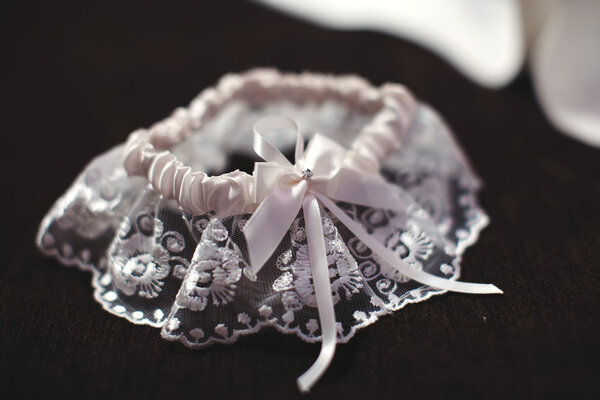 Garter on the leg of a bride. final preparation for wedding ceremony. Wedding day moments