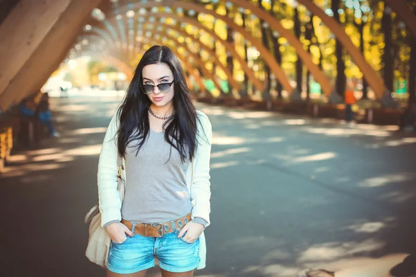Dospívající dívka v džínové kraťasy a sluneční brýle v parku — Stock fotografie