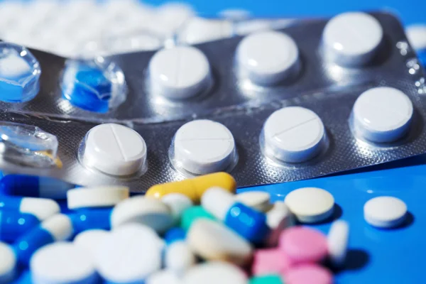 Pilules. Pilules médicales blanches sur fond bleu — Photo