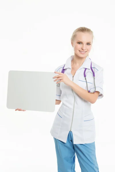 Portret van een glimlachende jonge dokter houden van een leeg vel papier op wit om uw tekst te schrijven. — Stockfoto