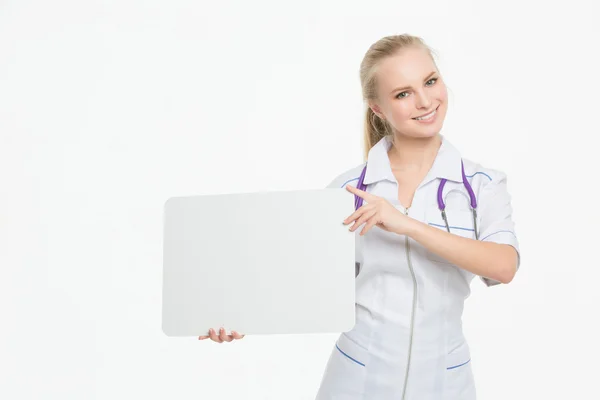 Portret van een glimlachende jonge dokter houden van een leeg vel papier op wit om uw tekst te schrijven. — Stockfoto