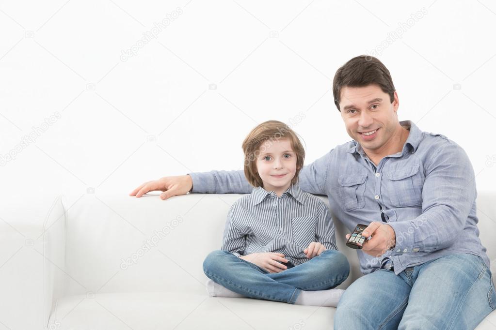 Father and son watching television together on the couch