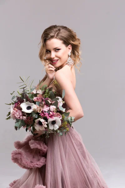 Mulher com cabelos longos encaracolados em um vestido rosa e flores do casamento . — Fotografia de Stock